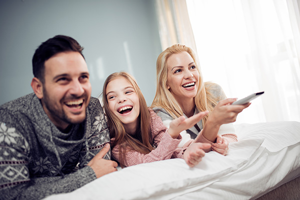 Family watching TV in bedroom,having great time together.
